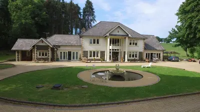 a large house with a fountain in the middle of a yard at Plas Y Dderwen Bed and Breakfast in Aberystwyth