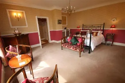 a bedroom with a bed and a table and chairs at Plas Y Dderwen Bed and Breakfast in Aberystwyth
