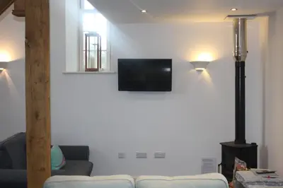 a living room with a couch and a television on a wall at Capel- Y-Bryniau in Pennal