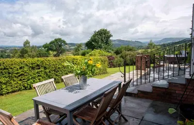 a table and chairs on a patio with a balcony at Wye Cottage in Builth Wells