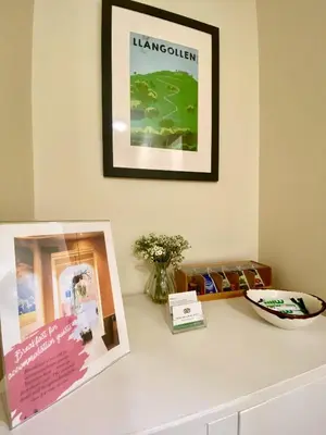 a table with a picture on the wall and a plate at RIVERBANC in Llangollen