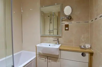 a bathroom with a sink and a tub and a mirror at The Old Black Lion in Hay-on-Wye