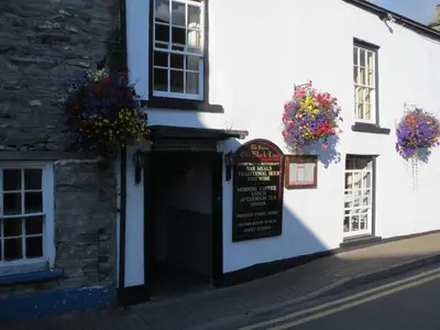 a white building with flower baskets on the side of it at The Old Black Lion in Hay-on-Wye