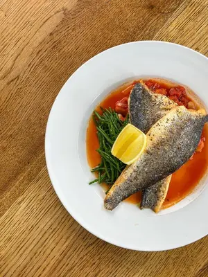 a bowl of fish soup with a lemon on a table at The Corbet Arms in Shrewsbury