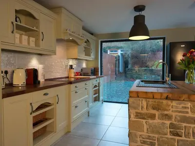 a kitchen with white cabinets and a stone wall at Chapel House Cottage in Builth Wells