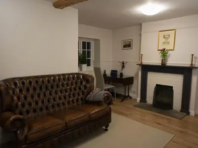a living room with a brown couch and a fireplace at Chapel House Cottage in Builth Wells