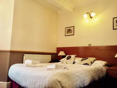 a bedroom with a large bed with white sheets at Plas Coch Hotel Ltd in Bala