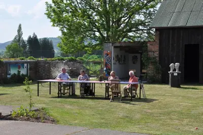 a group of people sitting around a table in a yard at Mid Wales Arts B&B in Caersws