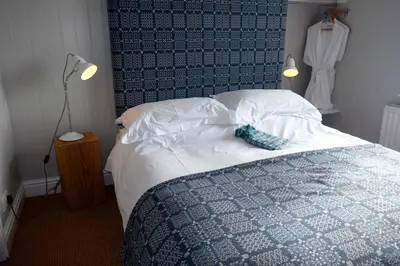 a bedroom with a bed with a blue and white comforter at Harbourmaster Hotel in Aberaeron