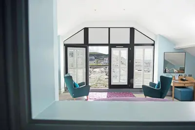 a room with two blue chairs and a window at Harbourmaster Hotel in Aberaeron