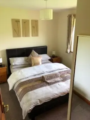 a bedroom with a large bed with white sheets at Nant-Y-Glyn in Llandrindod Wells