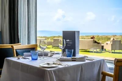 a table with two wine glasses and a window at Trefeddian Hotel in Aberdyfi