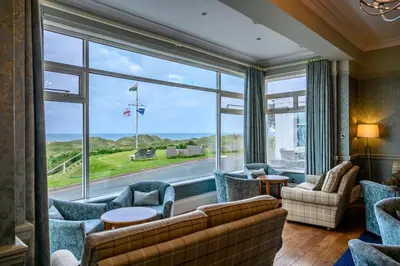 a living room with a couch and chairs and a large window at Trefeddian Hotel in Aberdyfi