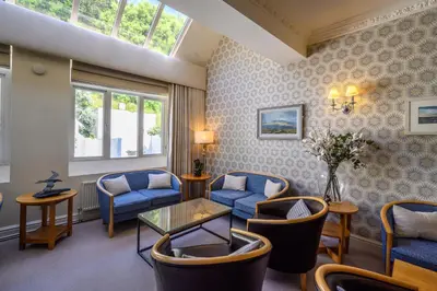 a waiting room with blue chairs and a table at Trefeddian Hotel in Aberdyfi
