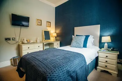 a bedroom with a bed and a tv on a wall at Trefeddian Hotel in Aberdyfi