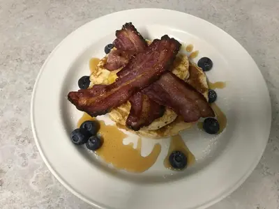 a plate of breakfast food with bacon and blueberries at Endeavour Guest House in Barmouth