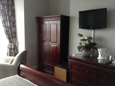 a bedroom with a dresser and a television on a dresser at Endeavour Guest House in Barmouth