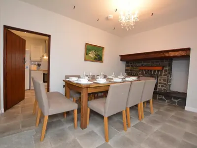 a dining room with a table and chairs and a fireplace at Pengarreg Fawr in Llanilar