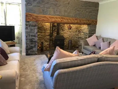 a living room with two couches and a stone fireplace at Pengarreg Fawr in Llanilar