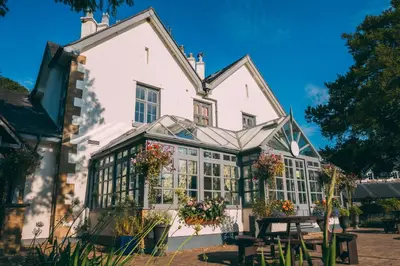 a large white house with windows and a table at Wild Pheasant Hotel & Spa in Llangollen
