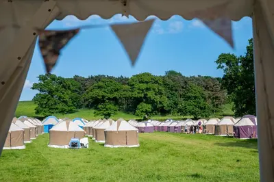a row of tents in a field with trees at Festival Yurts Hay-on-Wye in Hay-on-Wye