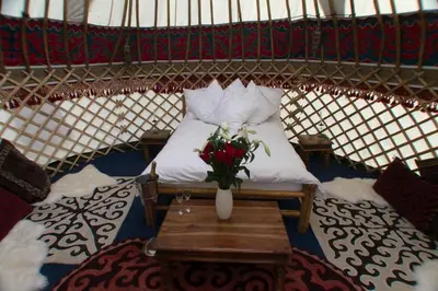 a bed in a yurt with a vase of flowers on a table at Festival Yurts Hay-on-Wye in Hay-on-Wye