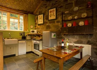 a kitchen with a wooden table and a counter top at Dolgenau Cottages in Trefeglwys