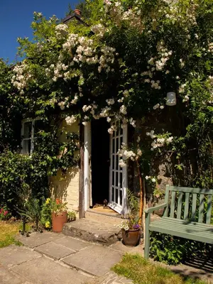 a green bench sitting in front of a house with flowers at Dolgenau Cottages in Trefeglwys