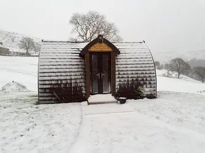 a small building with a door in the snow at Bwlcheinion Sea View Glamping in Machynlleth