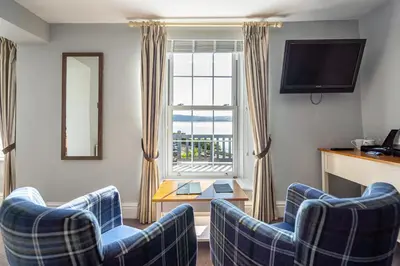 a living room with two blue chairs and a window at Penhelig Arms in Aberdyfi