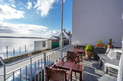 a balcony with tables and chairs and the water at Penhelig Arms in Aberdyfi