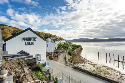 a building on a hill next to a body of water at Penhelig Arms in Aberdyfi
