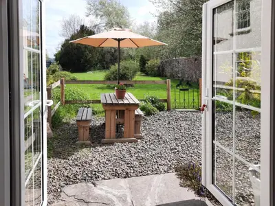 a patio with an umbrella and a table with a bench at The Cider Barn in Presteigne
