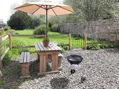 a picnic table with an umbrella and a grill at The Cider Barn in Presteigne