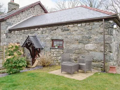 a stone building with two chairs in front of it at Ty Bach Twt in Dyffryn