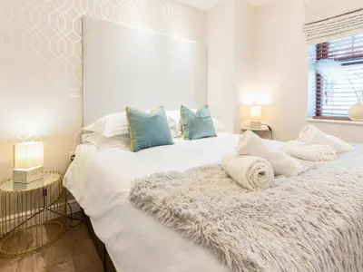 a white bedroom with a large white bed with blue pillows at Bwthyn Bach in Dyffryn