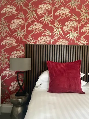 a bed with a red pillow and a red wall at The Lake Country House Hotel & Spa in Llangammarch Wells