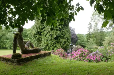 a statue in the middle of a garden with flowers at The Lake Country House Hotel & Spa in Llangammarch Wells