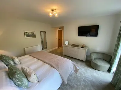 a bedroom with a bed and a chair and a television at The Lake Country House Hotel & Spa in Llangammarch Wells