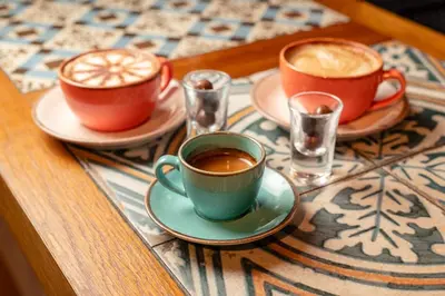 two cups of coffee sitting on a table at The Castle Of Brecon Hotel, Brecon, Powys - The Coaching Inn Group in Brecon