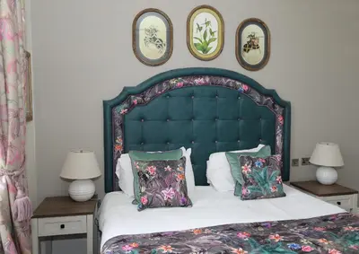 a bedroom with a large bed with a blue headboard and pillows at The Castle Of Brecon Hotel, Brecon, Powys - The Coaching Inn Group in Brecon