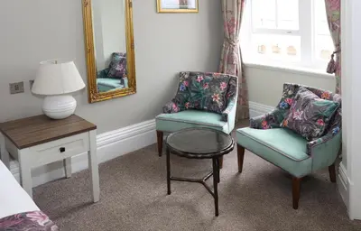 a bedroom with two chairs and a table and a mirror at The Castle Of Brecon Hotel, Brecon, Powys - The Coaching Inn Group in Brecon
