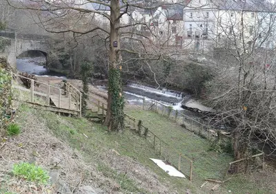 a river with a bridge and a waterfall at The Castle Of Brecon Hotel, Brecon, Powys - The Coaching Inn Group in Brecon