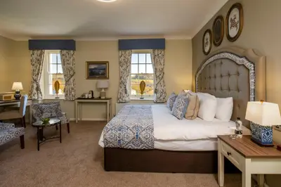 a bedroom with a large bed and a desk and chairs at The Castle Of Brecon Hotel, Brecon, Powys - The Coaching Inn Group in Brecon