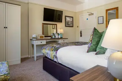 a hotel room with a large bed and a desk at The Castle Of Brecon Hotel, Brecon, Powys - The Coaching Inn Group in Brecon