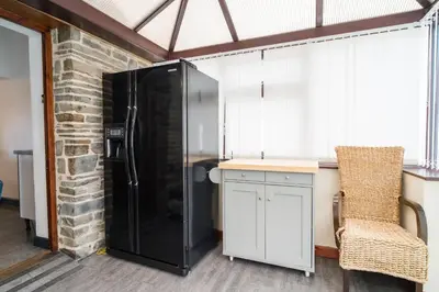 a kitchen with a black refrigerator next to a brick wall at The Barn in Aberystwyth