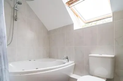 a bathroom with a tub and a toilet and a window at The Barn in Aberystwyth