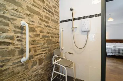 a shower in a room with a stone wall at The Barn in Aberystwyth