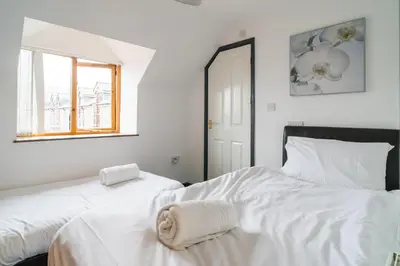 two beds in a bedroom with white sheets and a window at The Barn in Aberystwyth