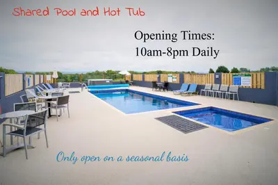 a swimming pool with tables and chairs on a patio at The Barn in Aberystwyth